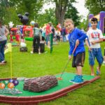 Smiling boy plays mini golf